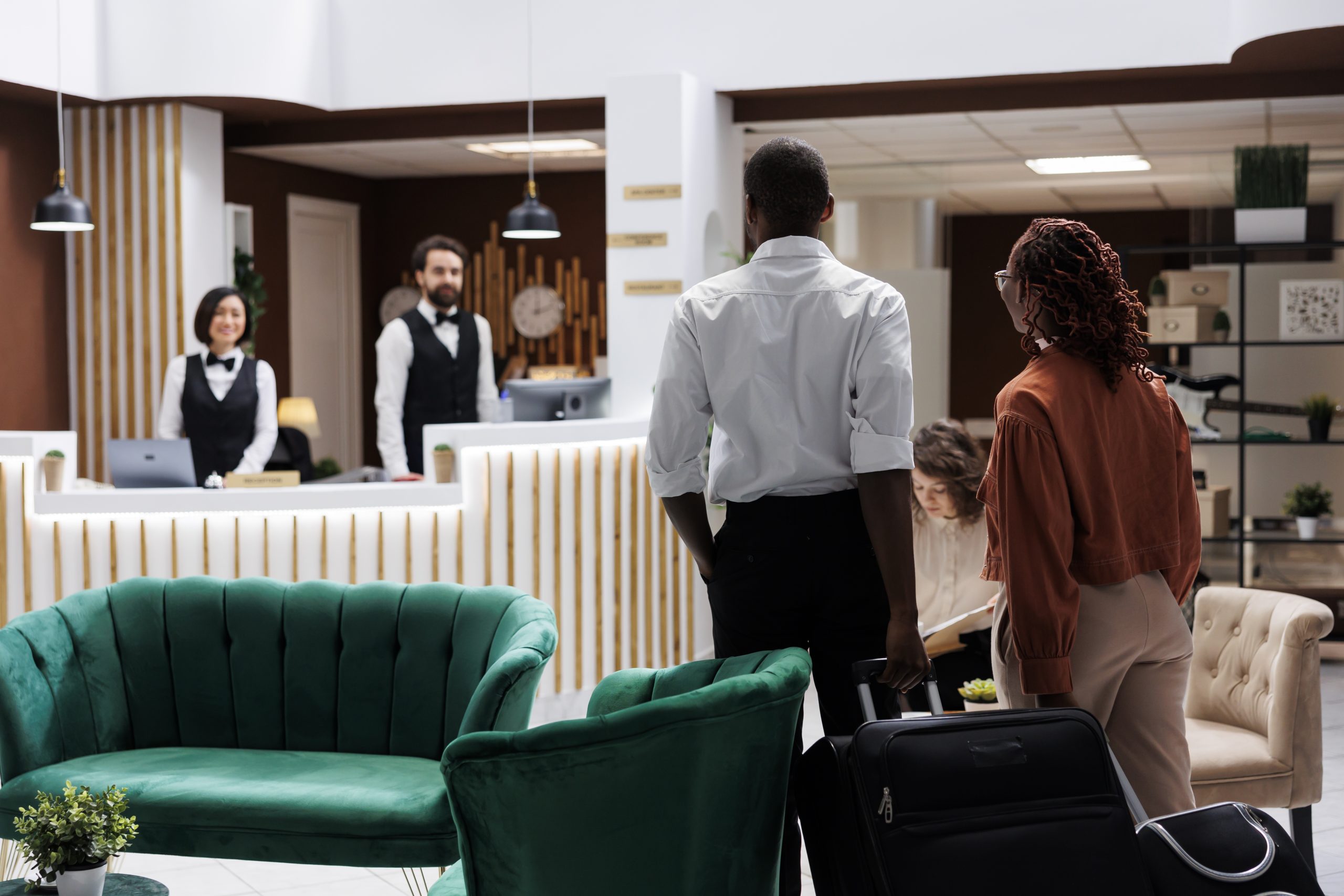 African american guests at front desk, arriving in hotel lobby and doing check in registration. Young partners talking to reception staff about accommodation and hospitality service.